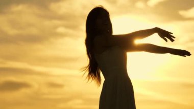 Gün batımında dans eden mutlu kız. Özgür kız sıcak güneşin altında bir partide dinleniyor. Müziğin içinde güzel hareketler. Okyanustaki bir adaya ineceğiz. Genç bir kızın komik yaşam tarzı.