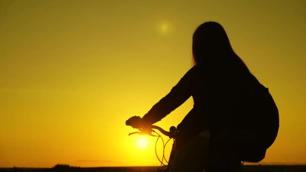 Lonely woman cyclist resting in park. Hiker healthy young woman stands on hill next to a bicycle, enjoying nature and sun. Free girl travels with a bicycle at sunset. concept of adventure and travel. — Stock Video