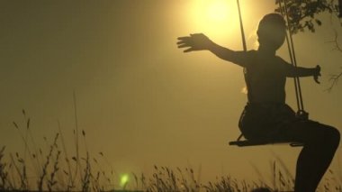 Çocuk parkta güneşin altında salıncakta sallanıyor. İp üzerinde sallanan genç bir kız meşe dalında sallanıyor. Genç kız yaz akşamı ormanda salıncakta sallanmaktan hoşlanıyor. Mutlu aile ve çocukluk kavramı.