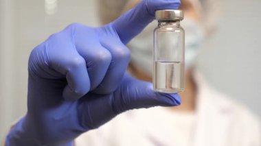 Bir hemşire elinde ilaçla bir ampul tutuyor. Hastalık aşısı doktor elinde. Covid 19. Doktor enjeksiyon tedavisi önerdi. Doktor hastaya iğne yapmaya hazır..