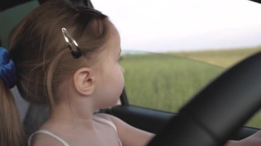 Babası küçük kızına direksiyon simidini çevirmeyi öğretiyor hem de sürücü koltuğunda otururken. Babam çocuklarla arabayla seyahat eder. Şoförle çocuk sürüyor. Mutlu aile ve çocukluk kavramı