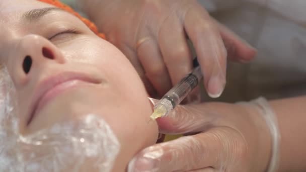 Cosmetologen handen in medische handschoenen maken een injectie in de huid van een vrouwengezicht. Schoonheidskliniek. Vrouw krijgt cosmetische gezichtsbehandelingen. Botox collageen injecties. jeugd- en schoonheidsconcept — Stockvideo