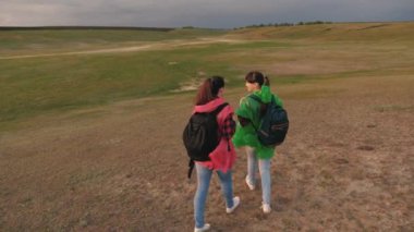 Özgür kadın gezginler vadiye gider. Takım çalışması gezginleri. Macera ve seyahat kavramı. Sağlıklı turist kızları renkli yağmurluklarla sırt çantalarıyla seyahat ederler. Fırtına yaklaşıyor..