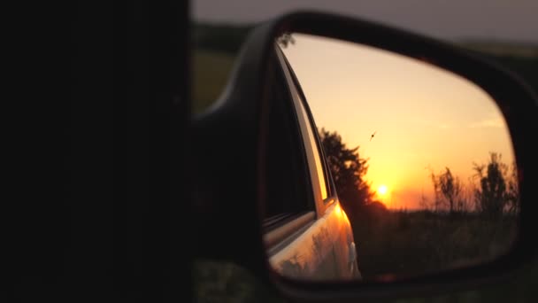 Een prachtige zonsondergang wordt weerspiegeld in de spiegel van de auto. het concept van avontuur en reizen. reizen met de auto buiten de stad. familie reis naar de natuur in een weekend — Stockvideo