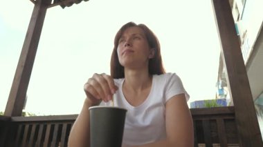 Güzel bir kadın caddedeki bir kafede sıcak bir kaşık karıştırıyor. Masanın üzerinde bir bardak kahve var, bir kız nefis aromalı kahve yapıyor..