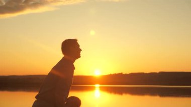 Babam mutlu küçük kızını kumsala atar, gün batımında eğlenir. Baba su kenarında çocuğuyla oynar. Mutlu aile kavramı. Güneşin üzerinde uçan bir baba ve sağlıklı bir çocuk silueti.