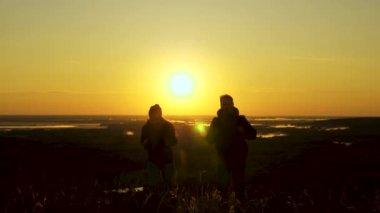 Özgür gezginler, sırt çantalı bir adam ve bir kadın, şafak sökerken dağlara tırmanıyorlar, zaferin, güneşin ve manzaranın tadını çıkarıyorlar. sağlıklı turistler gün batımında seyahat ederler. iş ekibi çalışması