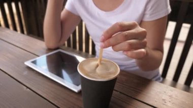 Kafedeki bir kız nefis aromatik kahve yapıyor ve tablet kullanıyor. Kadın sohbet ediyor, kahve içiyor ve dinleniyor. Bir kafede çalışmak ve içmek....