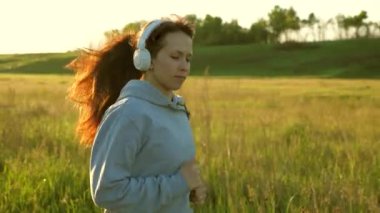 Özgür genç kadın yazın şafakta parkta antrenman yapıyor. Sağlıklı güzel kız spor yapıyor, kırsalda koşuyor. Koşucu kız temiz hava soluyor. Güneşin güzel ışıklarında akşam koşusu.
