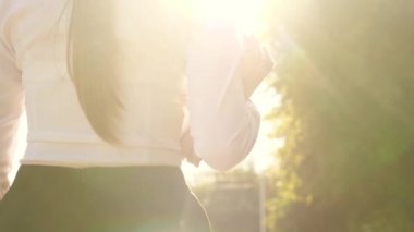 Öğrenci bir kız elinde ders kitaplarıyla güneşin parlak ışınlarıyla caddede yürür, kuşlar havalanır. Şehirdeki liseli kız. Ergen, elinde kitaplarla okula koşuyor..