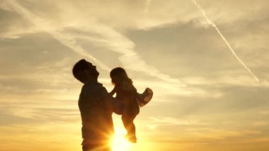 Babam mavi gökyüzüne mutlu bir kız çocuğu fırlatıyor. Baba ve küçük çocuk birlikte oynuyorlar, gülüyorlar ve sarılıyorlar. İyi yolculuklar. Bebeğin ebeveynin kollarında olması. Baba izinli. Mutlu aile kavramı.