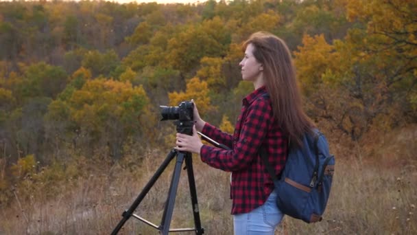 Свободная женщина путешественник с камерой делает красивые фотографии природы. Молодой независимый туристический фотограф фотографирует красивый осенний пейзаж с профессиональной цифровой камерой. концепция путешествия — стоковое видео