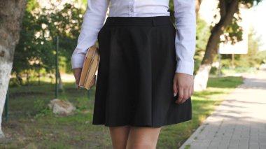 Bir öğrenci yaz parkında elinde ders kitaplarıyla caddede yürüyor. Şehirdeki liseli kız. Genç kız elinde kitaplarla okula koşuyor..