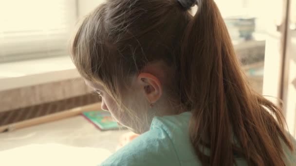Une écolière adolescente fait ses devoirs en écrivant des notes dans un cahier. Concept d'enseignement à distance. Étudiante, écolière est engagée dans l'auto-éducation assis à la table de la maison. enfant écrit des leçons. — Video