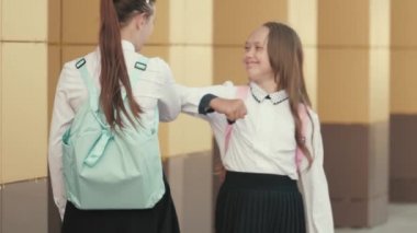 Okullu kızlar birbirlerini dirsekleriyle selamlarlar. Dirseklerinle selam ver. Okullu kızlar okula gider. Bir dirsek yardımı olmadan sınıf arkadaşlarını selamlar. Sosyal uzaklık, okula dönüş..