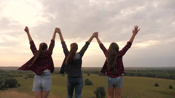 Niñas sanas, las mujeres van a la cima de la colina al atardecer, levantan las manos en el aire, felices e intoxicadas con la vida, la juventud y la felicidad. concepto de libertad de aventura, turismo y viajes — Foto de Stock