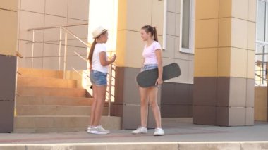 Kaykaylı kızlar dirseklerini selamlar ve sosyal ağda akıllı telefona bakarlar. Hey dirsekler. Sınıf arkadaşlarına dirseğiyle dokunmadan selam veriyor. Sosyal uzaklık, okula dönüş..