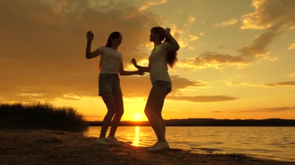 Celebrate a summer day with beach party. free girls are dancing cheerfully on summer evening at sunset. outdoor celebration. healthy teenagers cheerfully raise their hands up. a fun holiday on shore. — Stock Video