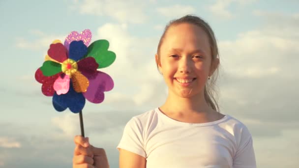 Ragazza che gioca a flipper park al rallentatore. Bambino felice che gioca divertendosi girandola. Felicità vacanza infanzia bambini felice vacanza in famiglia. concetto di infanzia. un bambino che gioca nel parco cattura il vento — Video Stock