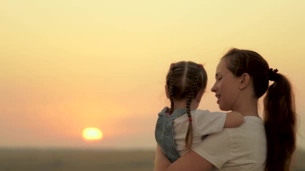 Mama bawi się z córką i pokazuje dziecku zachód słońca. Szczęśliwa rodzina, mama i córka na polu patrzą na słońce. Koncepcja szczęśliwej rodziny i zdrowych dzieci. dziecko kocha mamusię — Wideo stockowe