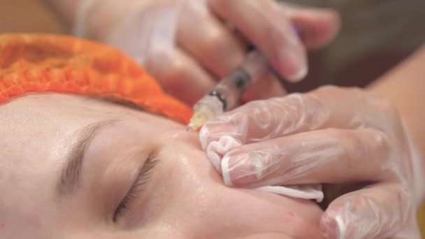 若者と美の概念です。美容師が医療用手袋を手に女性の顔の皮膚に注射します。美容クリニック。女性は化粧品の顔の治療を受ける。ボトックスコラーゲン注射. — ストック動画