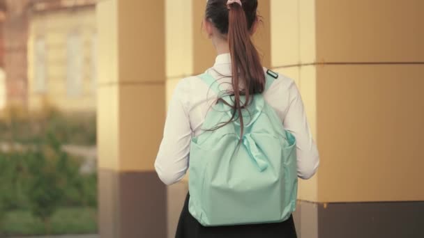 Teenage girl hurries to class. a school girl with a backpack goes down the street to school a beautiful young student goes to class. concept of education. — Stock Video