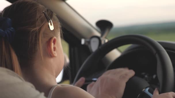 Dad teaches his little daughter to turn steering wheel while sitting in his car in drivers seat. father travels with children by car. driver and kid are driving. happy family and childhood concept — Stock Video