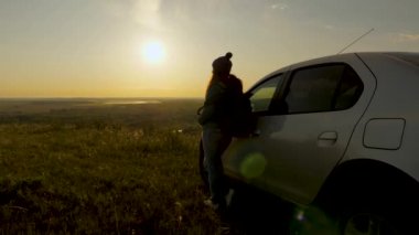 Kadın gezgin arabayla seyahat etmeyi sever. Orman ve nehrin üzerindeki gün doğumuna ve sise hayran olur. Sağlıklı bir kız arabanın yanında durur ve dağdan gelen güzel günbatımına hayran kalır. Özgür gezginler, turistler.