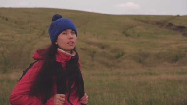 Vrije jonge vrouw wandelen in de bergen in het voorjaar, herfst. Actief gezond meisje loopt met een rugzak. Een eenzame reiziger loopt over de route. Recreatieconcept, biotoerisme, wandelen, avontuur. — Stockvideo