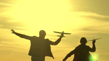 Çocukluk hayalleri pilot ve astronot olmak. Çocuklar ellerinde uçakla güneşin altında koşuyorlar. Mutlu çocukluk kavramı. Kızlar gün batımında oyuncak bir uçakla oynuyorlar..