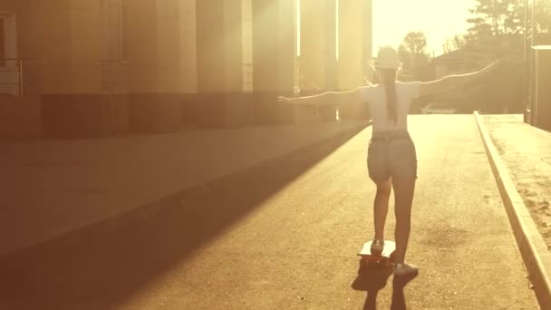 Estilo de vida são e ativo do adolescente moderno. menina bonita aprende a andar de skate ao ar livre sob o sol. passeios de skate felizes na estrada na cidade. — Vídeo de Stock