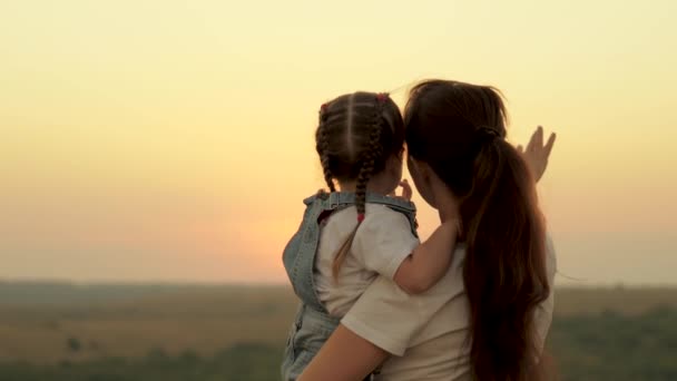 快乐的一家人在公园里散步，妈妈和女儿在田野里看着太阳。妈妈和女儿一起玩,给孩子看日落.幸福的家庭和健康的孩子的概念。宝宝爱妈妈 — 图库视频影像