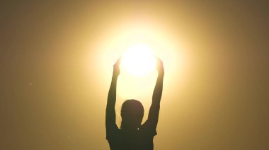 Çocuk oynuyor, güneş ışığını elleriyle yakalıyor. Barış, sevgi, nezaket kavramı. Özgür kız güneşi elinde tutuyor. Barış, ışık, sıcaklık kavramı. Güneş yıldızının avuçlarında bir gencin silueti..