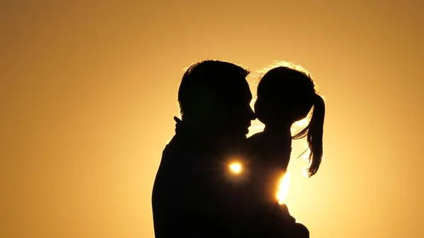 Babası sevgili sağlıklı kızını kollarının arasına alıyor. Gün batımında baba ve çocuğun silueti. Mutlu baba ve küçük çocuk parkta güneşin altında doğaya sarılıyorlar. Aile tatilde..