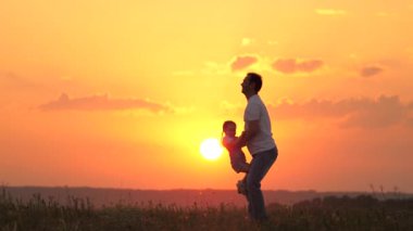 Baba küçük kızıyla oynuyor, neşeyle çocuğu gökyüzüne fırlatıyor. Doğada mutlu bir aile. Baba ve çocuk. Aile gün batımında tarlada dinleniyor. Temiz havada yürüyen mutlu ve sağlıklı bir aile..