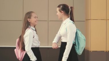 Okullu kızlar birbirlerini dirsekleriyle selamlarlar. Dirseklerinle selam ver. Okullu kızlar okula gider. Bir dirsek yardımı olmadan sınıf arkadaşlarını selamlar. Sosyal uzaklık, okula dönüş..