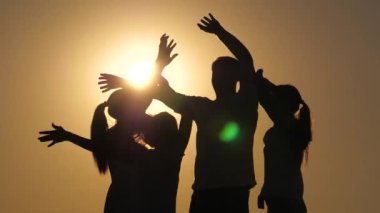 Gün batımında eğlenceli bir parti. Özgür genç kızlar ve bir adam güneşin altında sahilde dans ediyorlar. Sağlıklı kadınlar ve erkek dansları, gün batımında eğlenen insanlar. Hafta sonu kutlamalarında eğleniyorum..