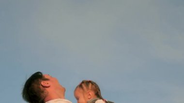 Baba ve küçük sağlıklı çocuk birlikte oynar, güler ve sarılırlar. Babam mavi gökyüzüne mutlu bir kız çocuğu fırlatıyor. Mutlu aile yolculukları. Bebeğin ebeveynin kollarında. Baba izinli. Mutlu aile kavramı