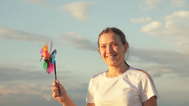 Glada barn leker ha kul nypa hjul. Lycka semester barndom lycklig familjesemester. tonårstjej som spelar pinwheel park i slow motion. barndomsbegreppet. ett barn som leker i parken fångar vind — Stockvideo