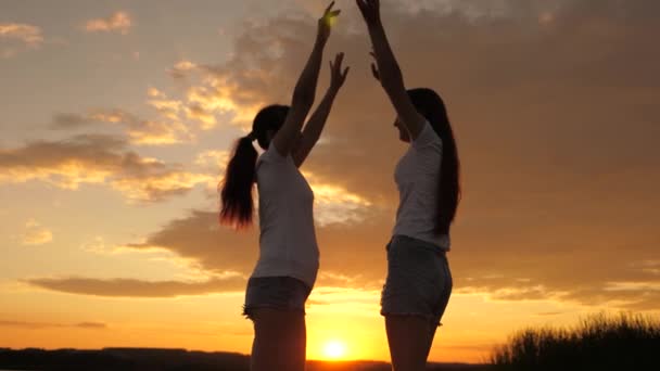 Free girls are dancing cheerfully on a summer evening at sunset. outdoor celebration. Celebrate a summer day with a beach party. healthy teenagers cheerfully raise their hands up. fun holiday on shore — Stock Video