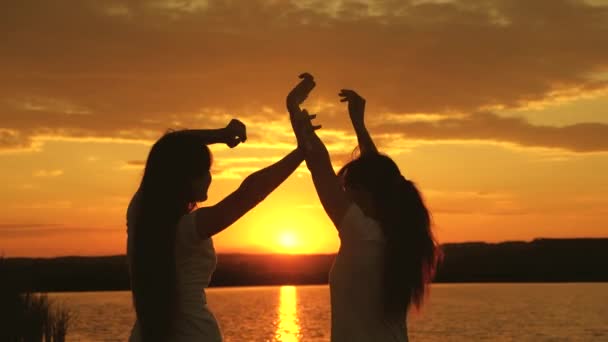 Gezonde tieners steken vrolijk hun handen op. leuke vakantie aan wal. vier een zomerdag met een strandfeest. gratis meisjes dansen vrolijk op een zomeravond bij zonsondergang. openlucht viering — Stockvideo