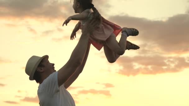 O pai vomita uma filha feliz no céu azul. moda pai em chapéu e pequena criança saudável jogar juntos, rir e abraçar. família feliz viaja. Bebê nos braços dos pais. Dia de folga do pai. uma família feliz — Vídeo de Stock