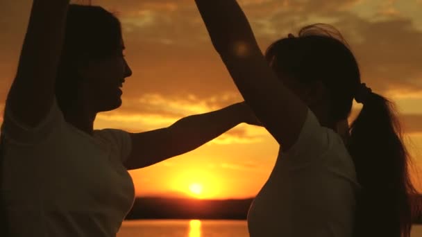 Free girls are dancing cheerfully on a summer evening at sunset. outdoor celebration. Celebrate a summer day with a beach party. healthy teenagers cheerfully raise their hands up. fun holiday on shore — Stock Video
