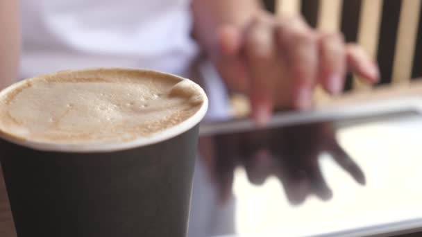 Mulher de negócios conversando, beber café e relaxar. jovem mulher em um café trabalha com um gadget. close-up. uma menina em um café de verão usa um tablet e bebe delicioso café aromático. — Vídeo de Stock