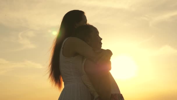 Happy family mom and daughter in a field at sunset. Mom hugs daughter, they admire beautiful sunset. concept of happy family of children and children. mother and baby walk in park, field, in sun — Stock Video