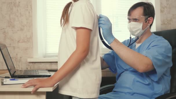 Pédiatre applique stéthoscope aux enfants dos, écoute le cœur et les poumons de l'adolescente. Le médecin pédiatre examine l'enfant. Le docteur écoute les battements de coeur des bébés. Enfant dans une chambre d'hôpital. — Video