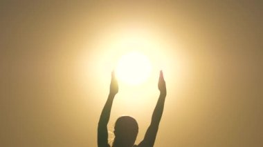 Güneş yıldızının avuçlarında bir gencin silueti. Çocuk oynuyor, güneş ışığını elleriyle yakalıyor. Barış, sevgi, nezaket kavramı. Özgür kız güneşi elinde tutuyor. Barış, ışık, sıcaklık kavramı.