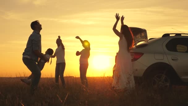 お父さんが遊んで楽しい娘を空に投げ込みお母さんと子供たちは日没時に踊ります。両親と子供は車で休憩するのをやめた。幸せな家族は車で旅をする。車の旅行の概念。健康な家族 — ストック動画