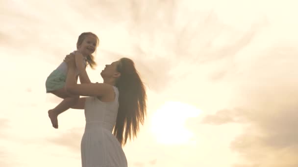 Mom throws her beloved healthy daughter up into the sky in her arms. happy mother and little healthy child are hugging in the park on nature in rays of sun. family on vacation. mom and baby at sunset. — Stock Video