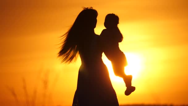 Familia feliz, mamá e hija en el campo al atardecer. Mamá está dando vueltas a su hijita al sol. Mamá y su amada hija juegan juntas. Familia feliz y concepto de infancia saludable — Vídeo de stock